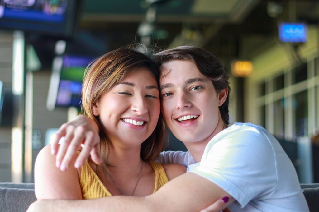 Happy young multiracial couple hugging while resting in cafe