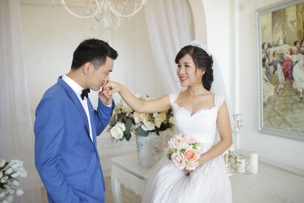 Man in Blue Suit Jacket Kissing Woman's Hand in White Wedding Dress