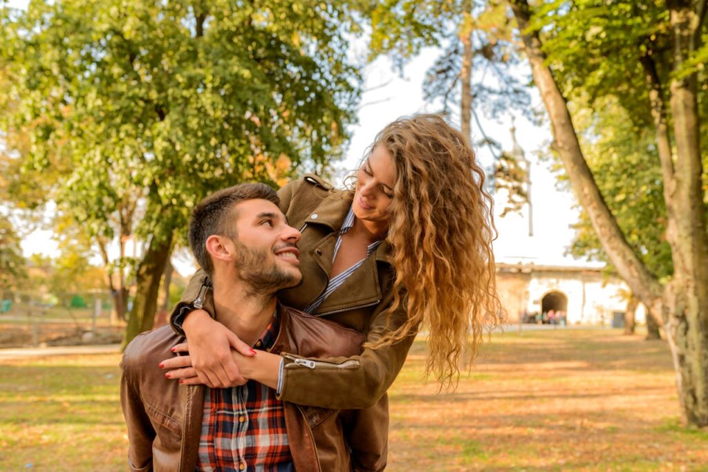 Man and Woman Wearing Wearing Brown Leather Jacket Near Green Leaf Tree